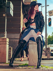 Exhibitionist Jeny Smith, wearing white tights, high leather boots and a black leather jacket, poses for a photoshoot on a crowded street.